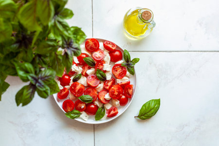 caprese salade served in a plate under a basil plant, home garden concept, top viewの写真素材