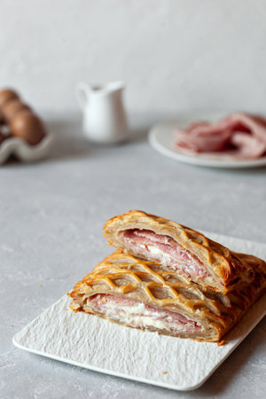 Puff with ham and cheese cut on a rectangular plate on a kitchen tableの写真素材