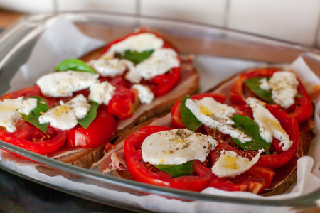 Ham, tomato, mozarella and basil leaves toastsの写真素材