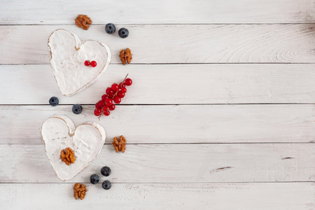 Heart shape cheese with berries and walnuts on the wooden backgroundの写真素材