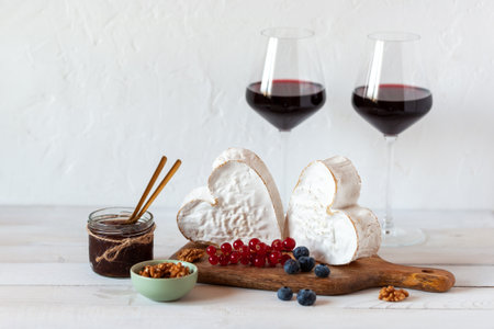 Heart shape cheese served with berries and two red wine glasses, Valentine Dayの写真素材