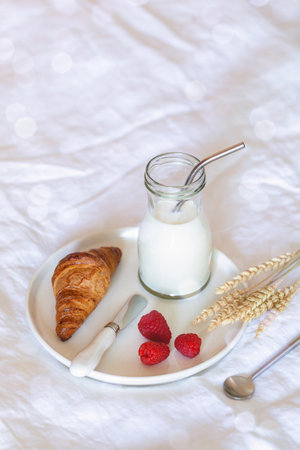 Coissant, milk and fresh berries, french breakfast on a badの写真素材