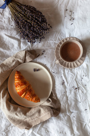 breakfast of croissant and hot chocolate served in a bed, top viewの写真素材