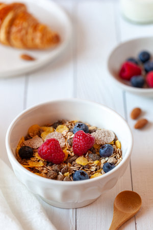 Breakfast bowl of oat flakes with berries, yoghurt and croissantの写真素材