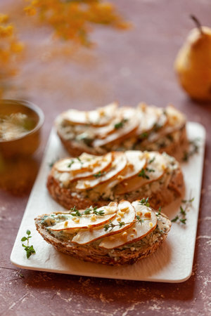 Roquefort french cheese and sliced peaches toasts on a square plateの写真素材