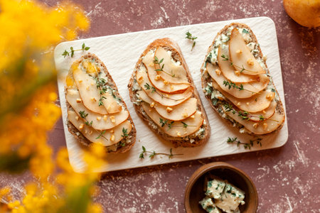 Roquefort french cheese and sliced peaches toasts on a square plateの写真素材