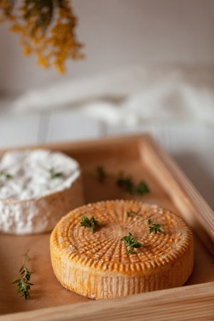 two cheese types decorated with thyme branches served on a wooden tray, side view, selective focus,の写真素材