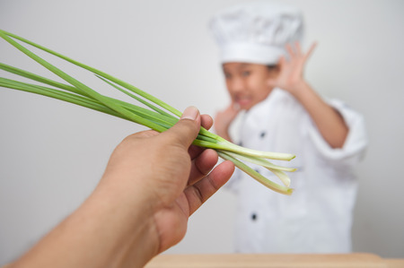 Little girl cook,children chef afraid of vegetables, scallion or Girls wear chef costumesの写真素材