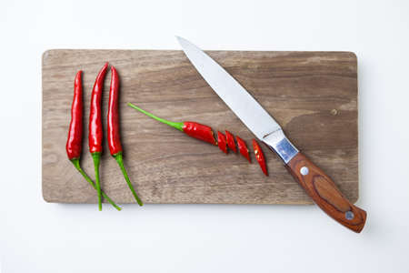 Chili peppers on a cutting board with knifeの写真素材