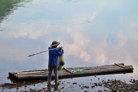 YANGSHUO, AUTONOMOUS REGION GUANGXI, CHINA, CIRCA JUNE 2016: The fisherman and the bamboo raftのeditorial素材