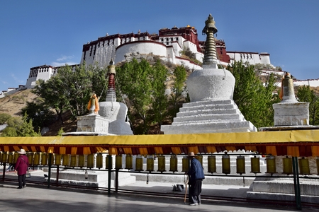 LHASA, TIBET AUTONOMOUS REGION, CHINA - CIRCA MAY 2018: People walking along tibetan prayer wheels  in front of Potala Palace  in Lhasa, Tibet Autonomous Region, China.のeditorial素材