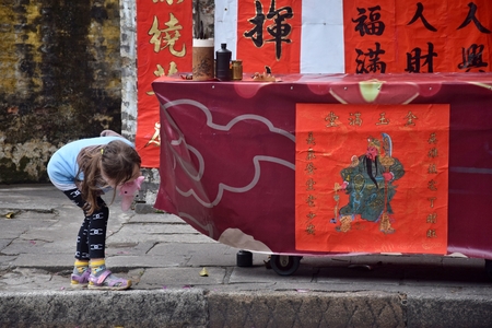 A little girl watches  a drawing of chinese general Guan Yu placed on the calligraper's stand. Translation of text: Happy and prosperious year.のeditorial素材