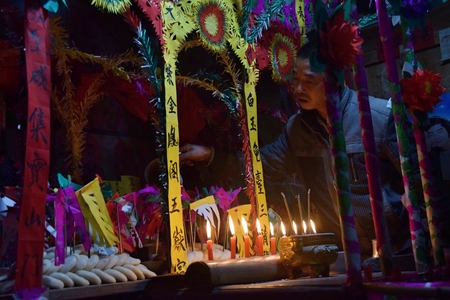 GUIZHOU PROVINCE, CHINA â CIRCA DECEMBER 2018: A man standing in front of colorful altar made in occasion the ritual redeeming the vow. Translation of text: worship nature and ancestors.のeditorial素材