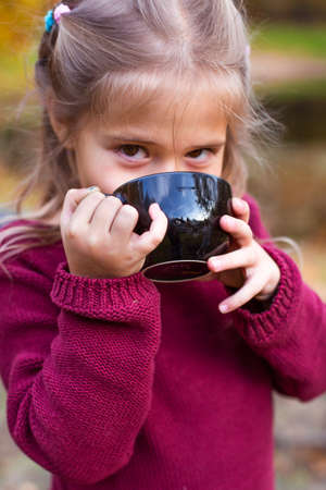children in the autumn forest on a picnic drinking teaの写真素材