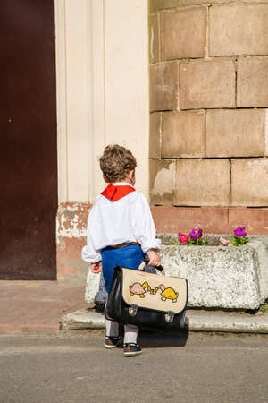 children in school uniforms with a briefcase walk near the schoolの写真素材