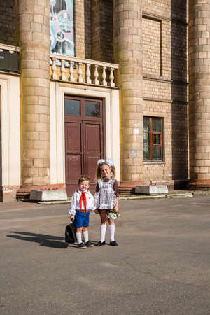 children in school uniforms with a briefcase walk near the schoolの写真素材
