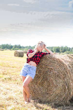 young woman sitting on hay baleの写真素材