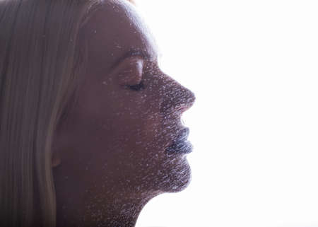 Beautiful woman applying spray water on face