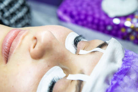 woman at spa salon applying false eyelashes