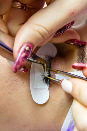 woman at spa salon applying false eyelashes