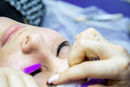 woman at spa salon applying false eyelashesの写真素材