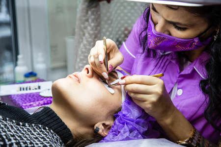 woman at spa salon applying false eyelashes