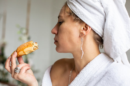 Young beautiful woman wearing white bathrobe having breakfast . Morning rituals.