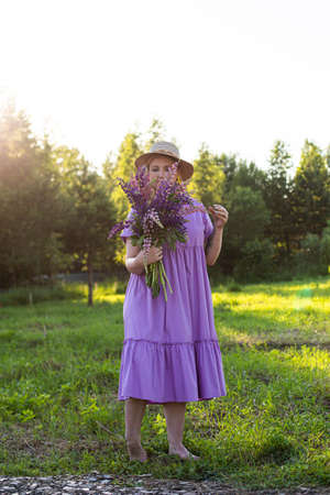 portrait of a girl in a blooming field in the sun at sunsetの写真素材