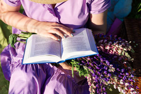 a girl with book in a blooming field in the sun at sunset