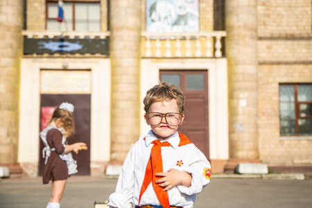 children in school uniforms with a briefcase walk and eat near the schoolの写真素材