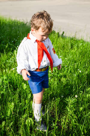 children in school uniforms with a briefcase walk and eat near the schoolの写真素材