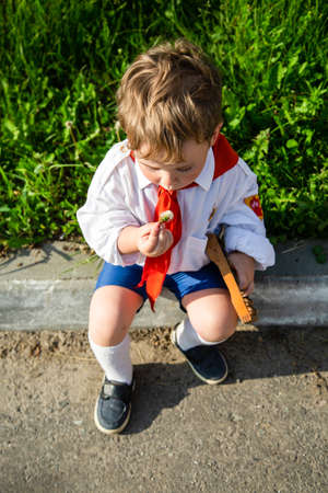 children in school uniforms with a briefcase walk and eat near the schoolの写真素材
