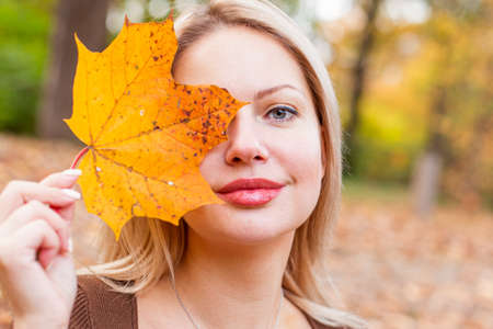 happy smiling woman holding in her hands yellow maple leaves