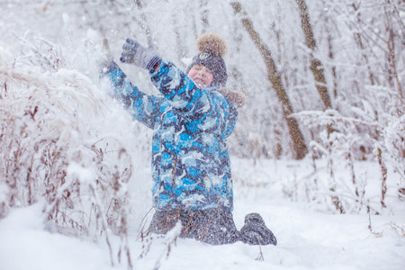 boy throwing snow in the air at sunny winter day, back viewの写真素材