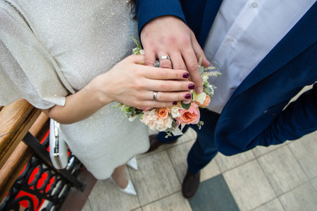 Hands of the groom and the bride on a wedding bouquetの写真素材