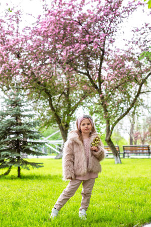 a girl in a light fur coat walks among flowering treesの写真素材