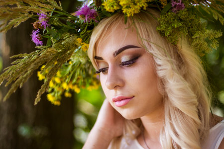 girl in a beautiful wreath walks through the summer meadowの写真素材