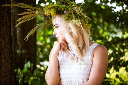 girl in a beautiful wreath walks through the summer meadowの写真素材