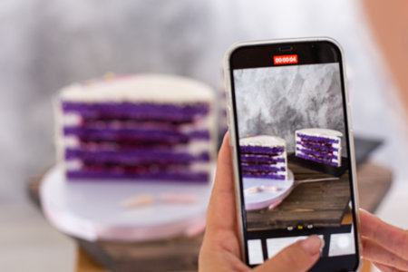 Girl photographs a cake with her smartphoneの写真素材