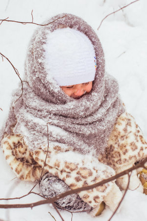 Winter portrait of cute smiling child girl on the walk in sunny snowy forestの写真素材