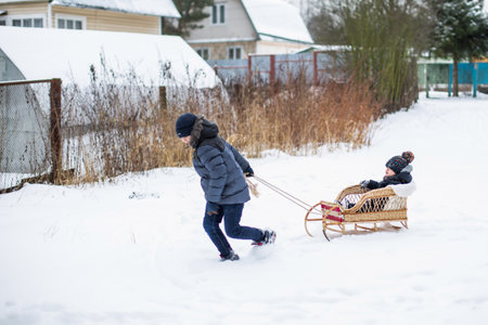Boy pulling his friend on a sledgeの写真素材