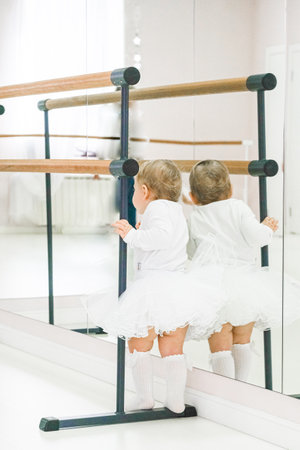 Portrait of a cute baby ballerina sitting near the ballet barre putting on shoes. videoの写真素材