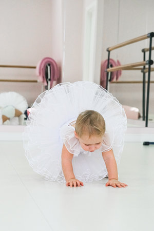Portrait of a cute baby ballerina sitting near the ballet barre putting on shoes. videoの写真素材