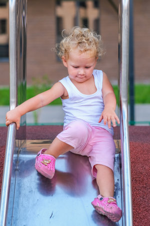Young girl playing and sliding down a slideの写真素材