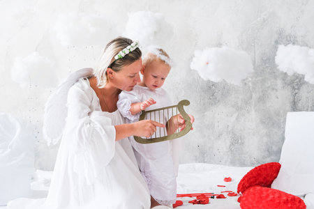 Beautiful mother and her toddler daughter wearing angel costumesの写真素材