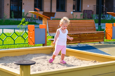 Child playing in the sandbox in the playground in the courtyard of a houseの写真素材