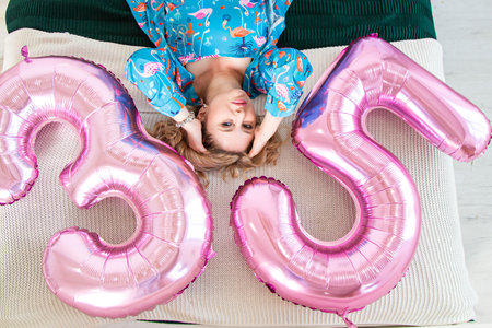 Girl lying on a bed with balloonsの写真素材