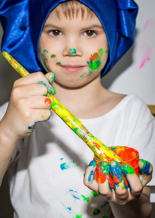 Smiling young boy with paint on his hands and faceの写真素材
