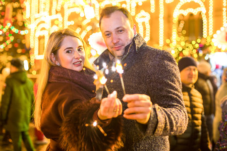 Romantic couple in love hugging and burning the sparklers at festive street fairの写真素材