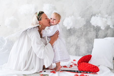 Beautiful mother and her toddler daughter wearing angel costumes. High quality photo